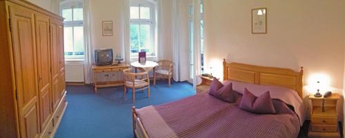 a bedroom with a bed and a table with a chair at Bilz-Pension in Radebeul