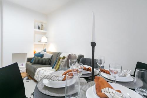 uma sala de jantar com uma mesa com óculos e um sofá em kings cross St Pancras luxury apt em Londres