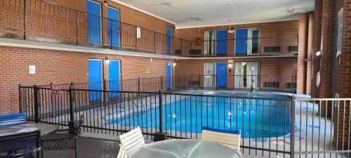 een zwembad in een gebouw met tafels en stoelen bij Fairview Inn & Suite in Jonesboro