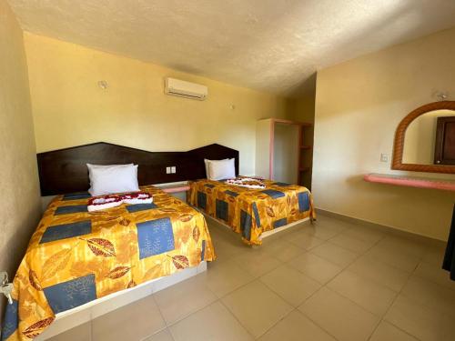 um quarto de hotel com duas camas e um espelho em Hotel Posada Purépechas em Zihuatanejo
