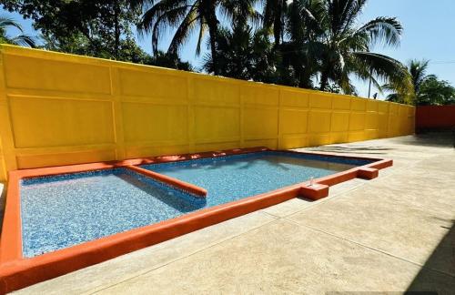 een zwembad met een geel hek bij Hotel Posada Purépechas in Zihuatanejo
