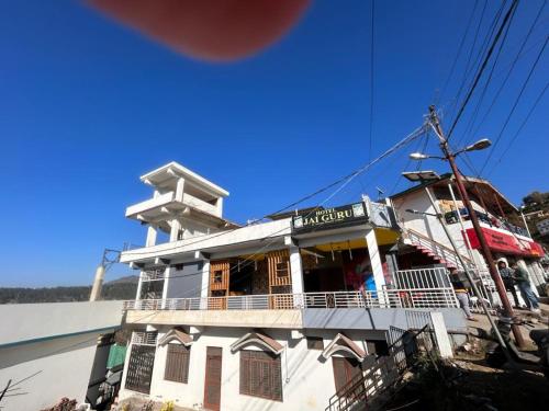 a white building with a balcony on top of it at Hotel Jai Guru in Almora