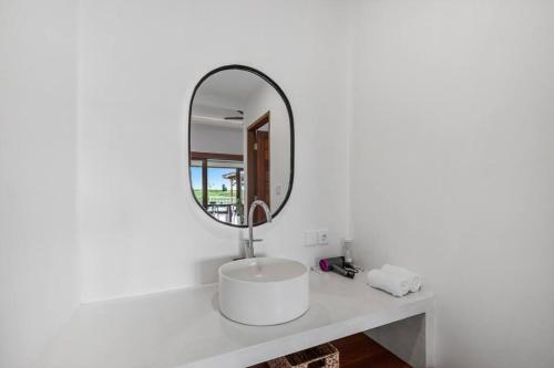 uma casa de banho branca com um lavatório e um espelho em Villa Swantika: Infinity Pool Aussicht Canggu em Canggu