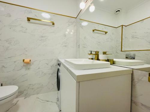 Baño blanco con 2 lavabos y aseo en Luxury apartment en Cluj-Napoca