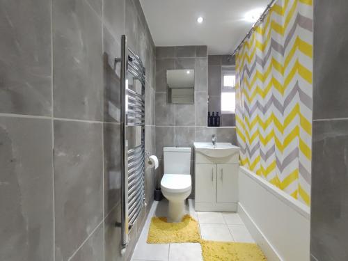 a bathroom with a toilet and a yellow and gray wall at Elegant 3-Bedroom Home, sleeps up to 5 guest. in South Ockendon