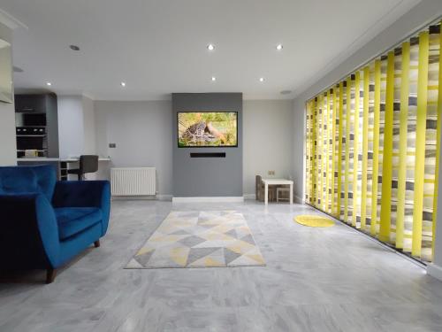 a living room with a blue couch and yellow curtains at Elegant 3-Bedroom Home, sleeps up to 5 guest. in South Ockendon
