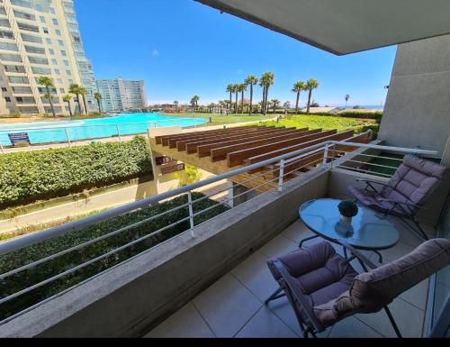een balkon met een tafel en stoelen en een zwembad bij Dpto duplex 2 dormitorios 2 baños en Laguna Vista ,Algarrobo in Algarrobo