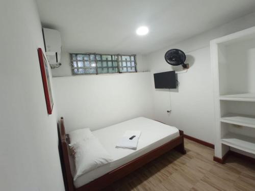 a small white room with a bed and a window at Hostal El Mohan in Neiva