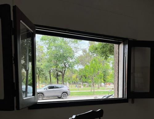 una ventana con vistas a un coche estacionado en un parque en Casa Céntrica totalmente equipada !!! en Santiago del Estero