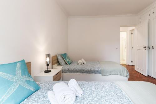 1 dormitorio con 2 camas y toallas. en Cascais Beach Flower Apartment en Estoril