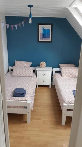 une chambre avec deux lits et un mur bleu dans l'établissement Le Sanderling, à Trégunc