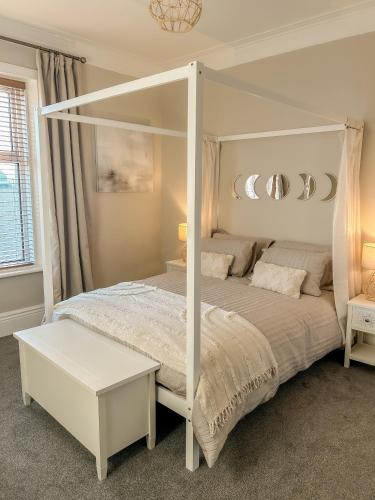 a bedroom with a white canopy bed and a table at Paupies Place Seaside Stay in Cullercoats