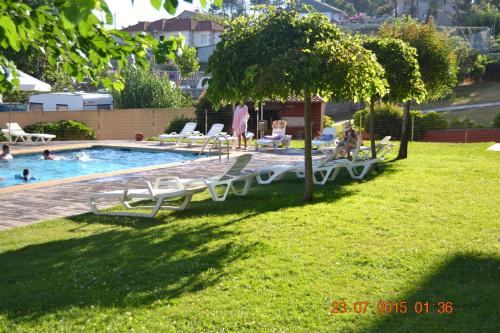 basen z leżakami i drzewo w trawie w obiekcie Apartamentos Montalvo Playa w mieście Montalvo