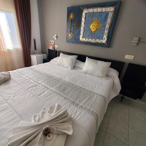 a bedroom with a large white bed with a painting on the wall at Ampuria Inn in Empuriabrava