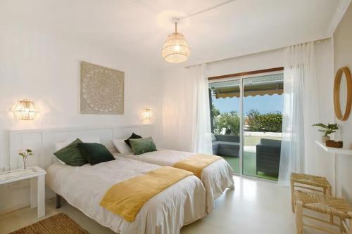 a white bedroom with two beds and a window at House Experience Villa Violeta in La Victoria de Acentejo
