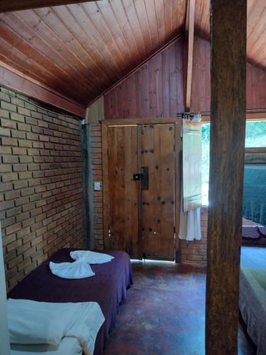 a bedroom with two beds and a brick wall at Pousada Toque de Minas in Visconde De Maua