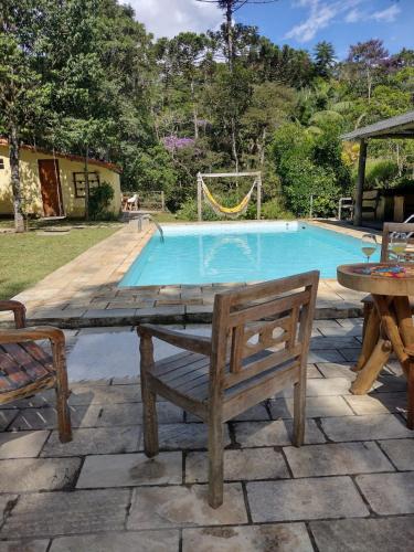 a pool with a bench and a table and a swing at Pousada Toque de Minas in Visconde De Maua