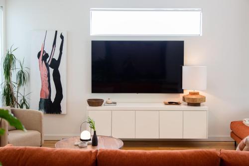 a living room with a large television on a white cabinet at Luxury Norwood Retreat in Norwood