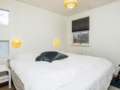 a white bedroom with a large white bed with a pillow at 6 person holiday home in Løkken-By Traum in Løkken