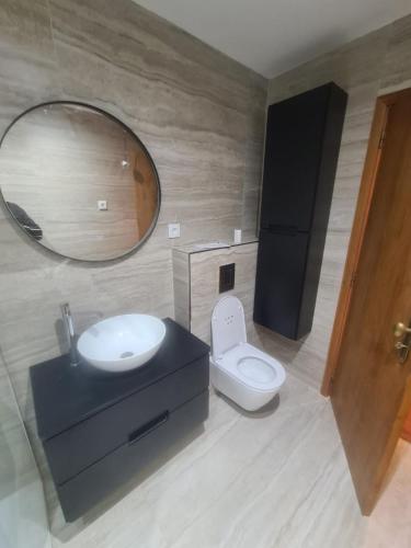 a bathroom with a sink and a toilet and a mirror at Deluxe Apart in Furadouro