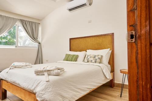a bedroom with a bed with white sheets and a window at Aaki Hotel in Las Peñitas