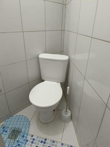 a white toilet in a white tiled bathroom at Duplex com dois Quartos in Salvador
