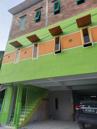un edificio verde con un coche aparcado delante de él en kost maqmil en Prambanan