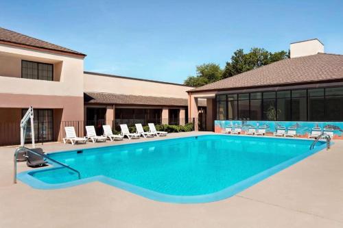 a large swimming pool with chairs and a building at Inn & Suites at Fort Gregg-Adams in Prince George