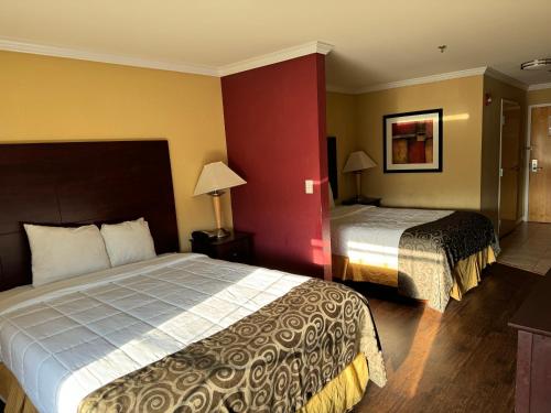 Habitación de hotel con 2 camas y pared roja en Inn & Suites at Fort Gregg-Adams en Prince George