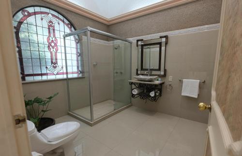 a bathroom with a shower and a toilet and a window at Gran Hotel Firenze in Tequisquiapan