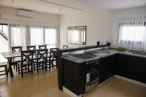 a kitchen with a stove and a table with chairs at Departamento con terraza y quincho con asador in Salta