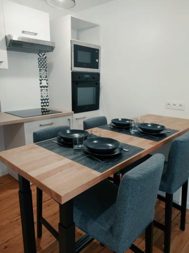une table en bois avec des assiettes et des verres dans l'établissement C'COZY - grande maison calme et lumineuse, à Sablé-sur-Sarthe