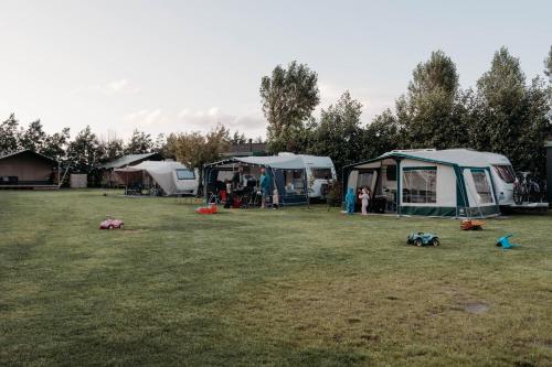 a group of tents parked in a field at Camping De Tulpenweide lege Kampeerplaats, lege plaats op het gras zonder bed in Breezand