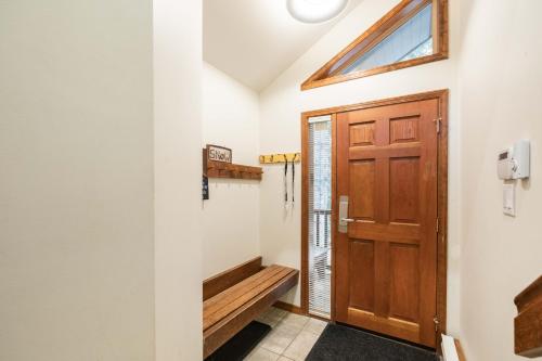 korytarz z drewnianymi drzwiami i ławką w obiekcie Blackcomb Greens by Outpost Whistler w mieście Whistler