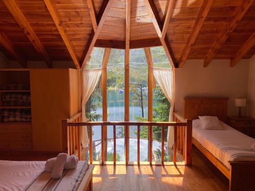 1 dormitorio con 2 camas y ventana grande en BOG Le Pommier - Cabañas con vista al lago y piscina climatizada en Villa La Angostura