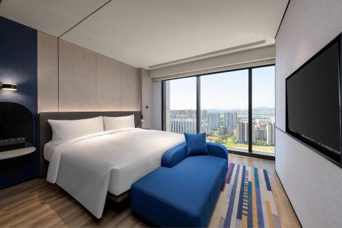 sypialnia z dużym łóżkiem i dużym oknem w obiekcie Aloft Yantai w mieście Yantai