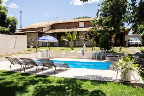 a house with a pool and two chairs and an umbrella at Casa das Pedras in Lagoa Santa