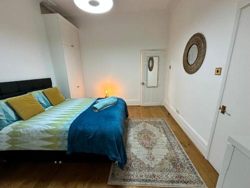um quarto com uma cama com lençóis azuis e um tapete em Cosy one bedroom flat em Londres