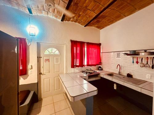 une cuisine avec des fenêtres rouges et un comptoir dans l'établissement Bungalows Las Glorias, à Rincon de Guayabitos