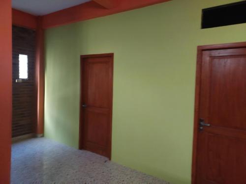 um quarto com paredes verdes e portas de madeira em kost maqmil em Prambanan