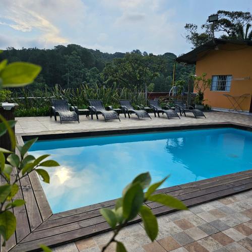 a swimming pool with chaise lounge chairs around it at Casa de campo em sítio de médio padrão com piscina aquecida e churrasqueira in Juquitiba