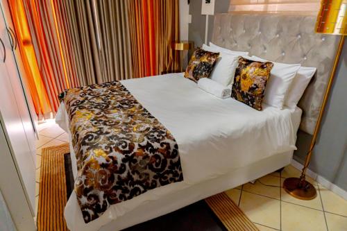 a bedroom with a large bed with white sheets and pillows at Homes of Ace Gold in Pretoria