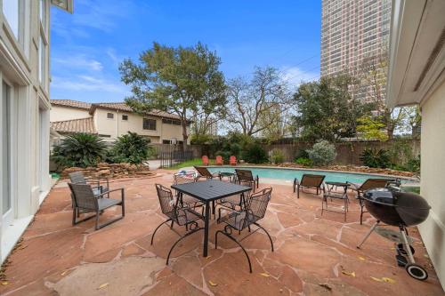 een patio met een tafel en stoelen naast een zwembad bij Galleria Pool Games Movie Poker Room Sleep 16 in Houston