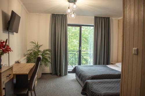 ein Hotelzimmer mit einem Bett, einem Schreibtisch und einem Fenster in der Unterkunft Готельно-ресторанний комплекс Фамілія in Bushtyno
