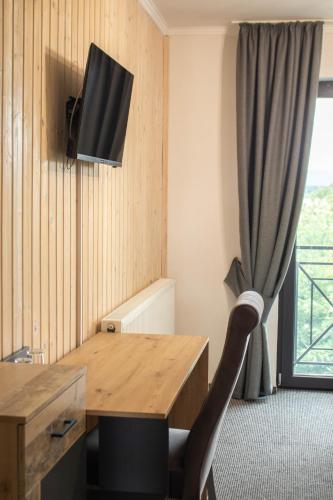 a room with a wooden table with a chair and a television at Готельно-ресторанний комплекс Фамілія in Bushtyno