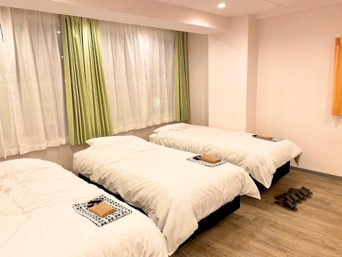 three beds in a room with green curtains at Sakura Hotel Jimbocho in Tokyo