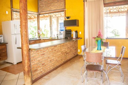 a kitchen with yellow walls and a counter with chairs at Casa das Pedras in Lagoa Santa