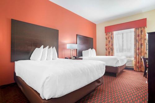 two beds in a hotel room with orange walls at Best Western Plus Flowood Inn & Suites in Flowood