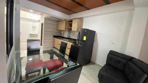 a living room with a glass table and a kitchen at Apartamento Confort Quindío in Calarcá