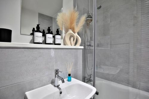 a bathroom with a sink and a shower with bottles on a shelf at KA Propertiess - 2Bed & 2Baths Ensuite, Parking, Balcony, Wi-Fi, Netflix, Media City in Manchester
